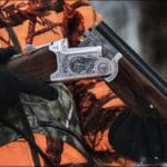 Hunter Hunting in winter with over-under shotgun wearing blaze orange hunting clothing
